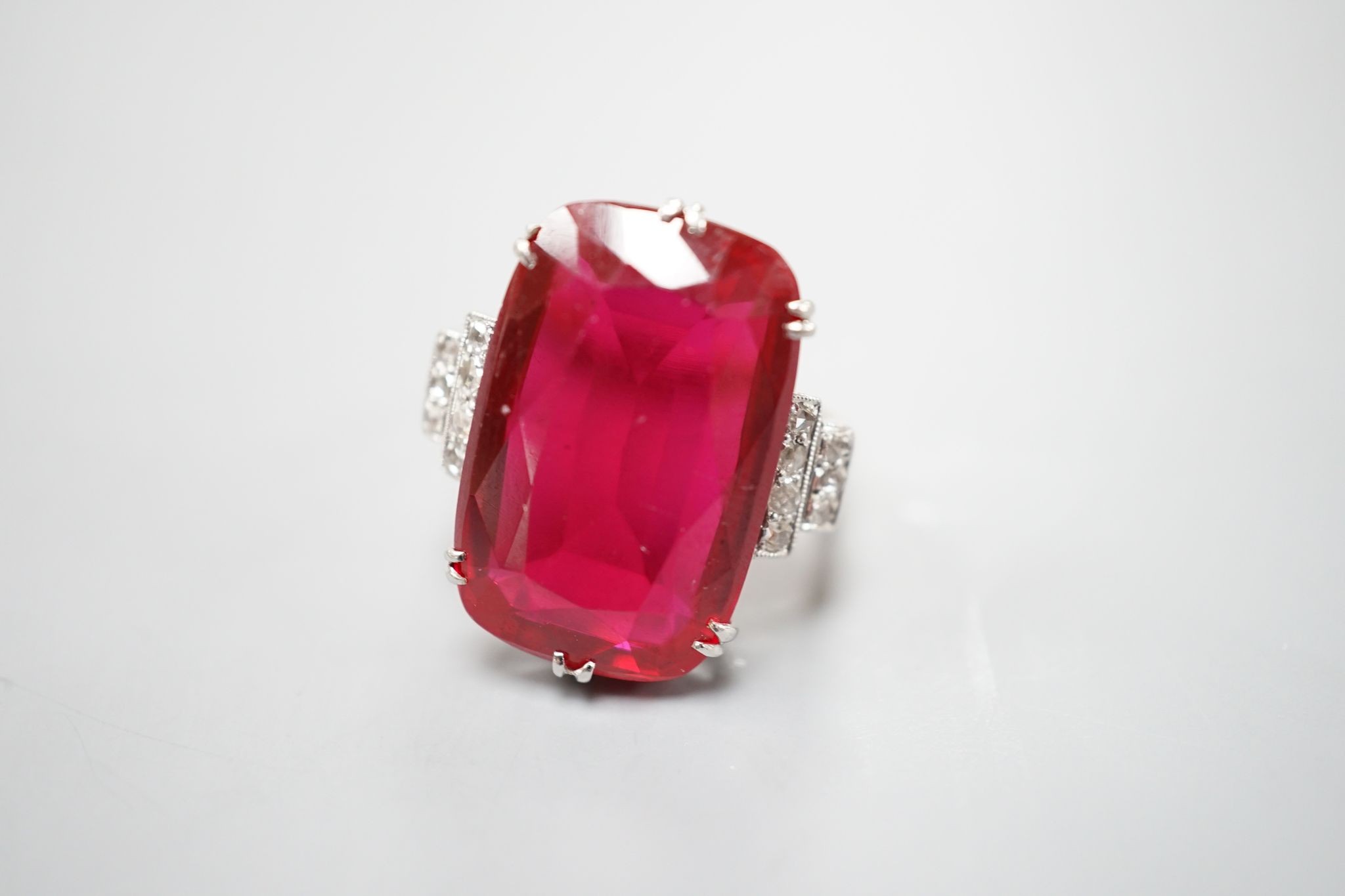 A yellow metal and large synthetic ruby set dress ring, with rose cut diamond set stepped shoulders, size L/M, gross weight 8 grams.